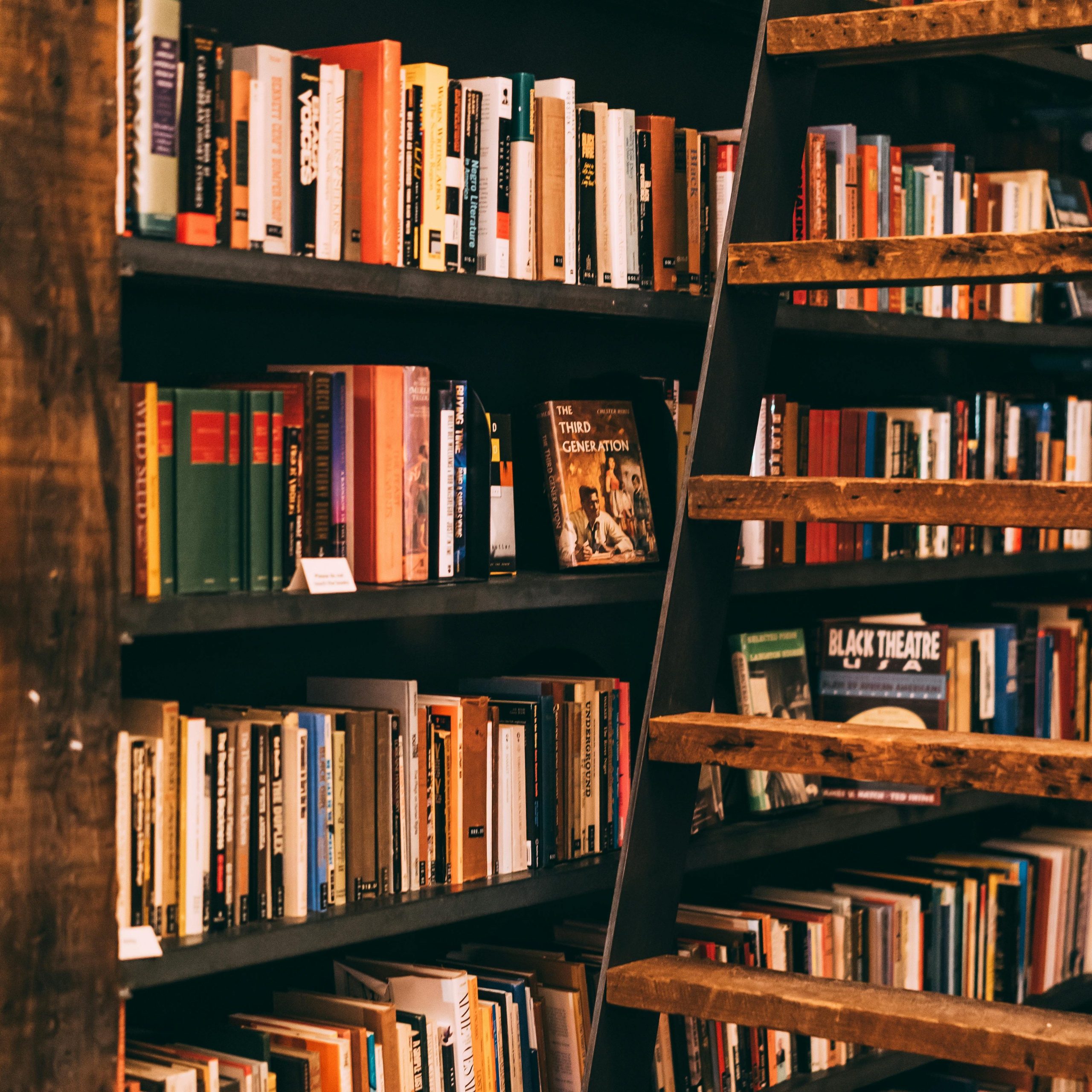 A shelf in a library where a lot of books are available to choose from to read.