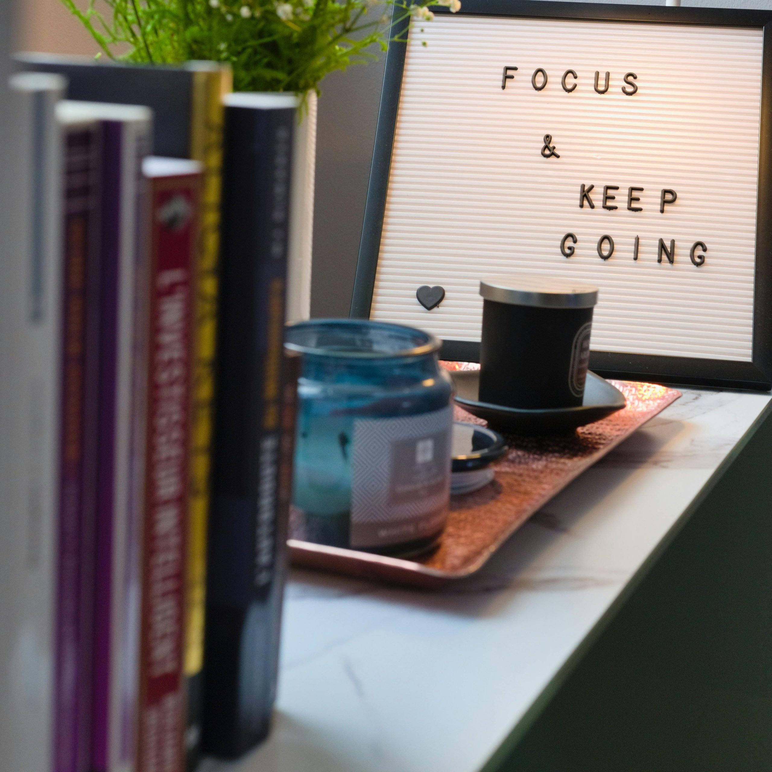 A table with books on one end and a quote which says focus and keep going.